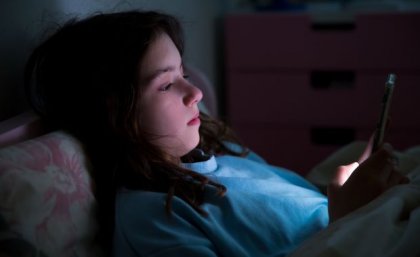 a girl's face is illuminated by the light of a phone screen